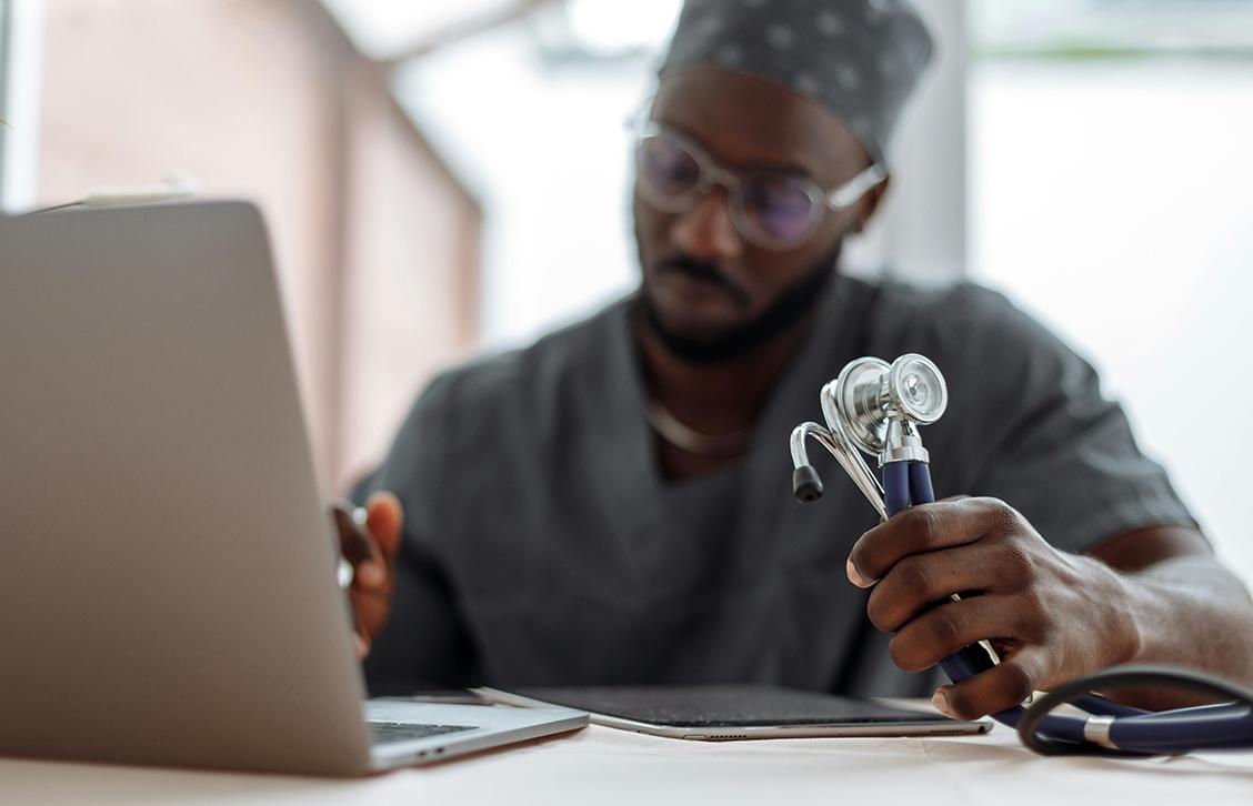 Médico à frente do computador portátil a analisar caso clínico