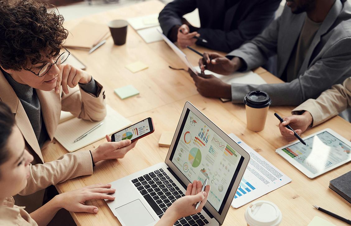 equipa em mesa de trabalho com computadores portáteis e documentos